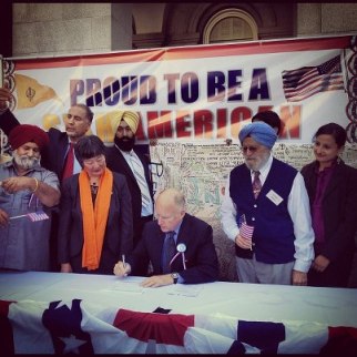 California Governor Jerry Brown (seated) signs AB1964 and SB1540 into law at a rally at the California State Capitol last Saturday. Assembly Member Mariko Yamada (standing left of the Governor), Dr. Onkar Bindra (standing right of the Governor) and Sikh Coalition Advocacy Manager Simran Kaur (far right) joined the Governor. (source: Instagram user i2theb)