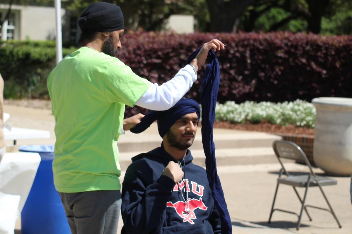 "SMU Sikh Students Association President Parminder Deo ties a turban around student Alli Schloeman." (source: Christopher Saul / The Daily Campus)